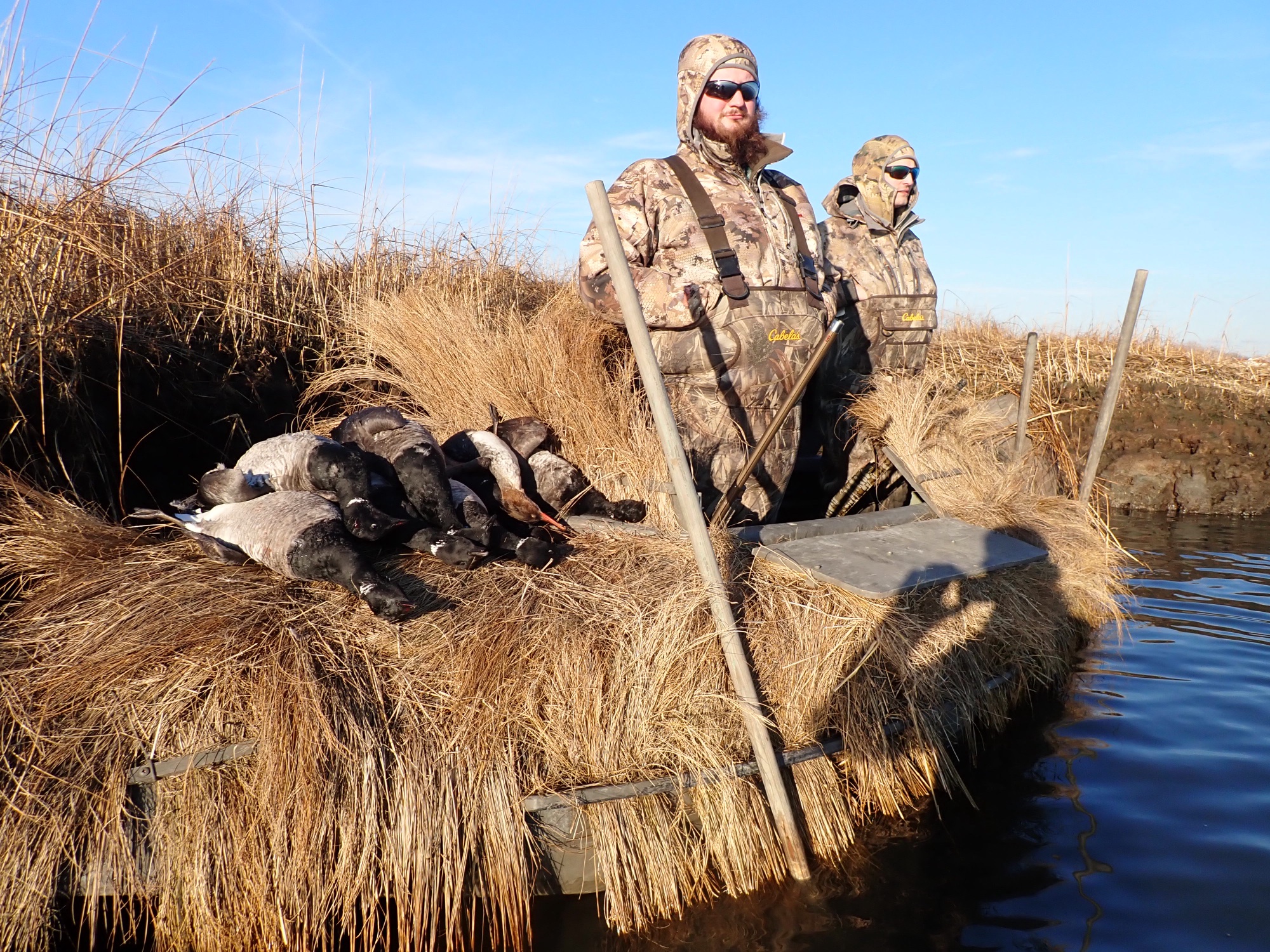 Hunters in a traditional grass boat on a Long Island tidal marsh creek
